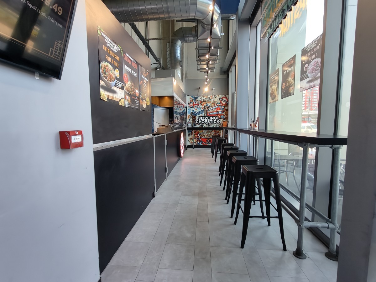From entrance facing right. High table and stools along right wall. Counter on left wall.