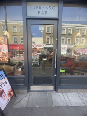 Glass door with black frame ahead. Push silver metal handle on right to open.