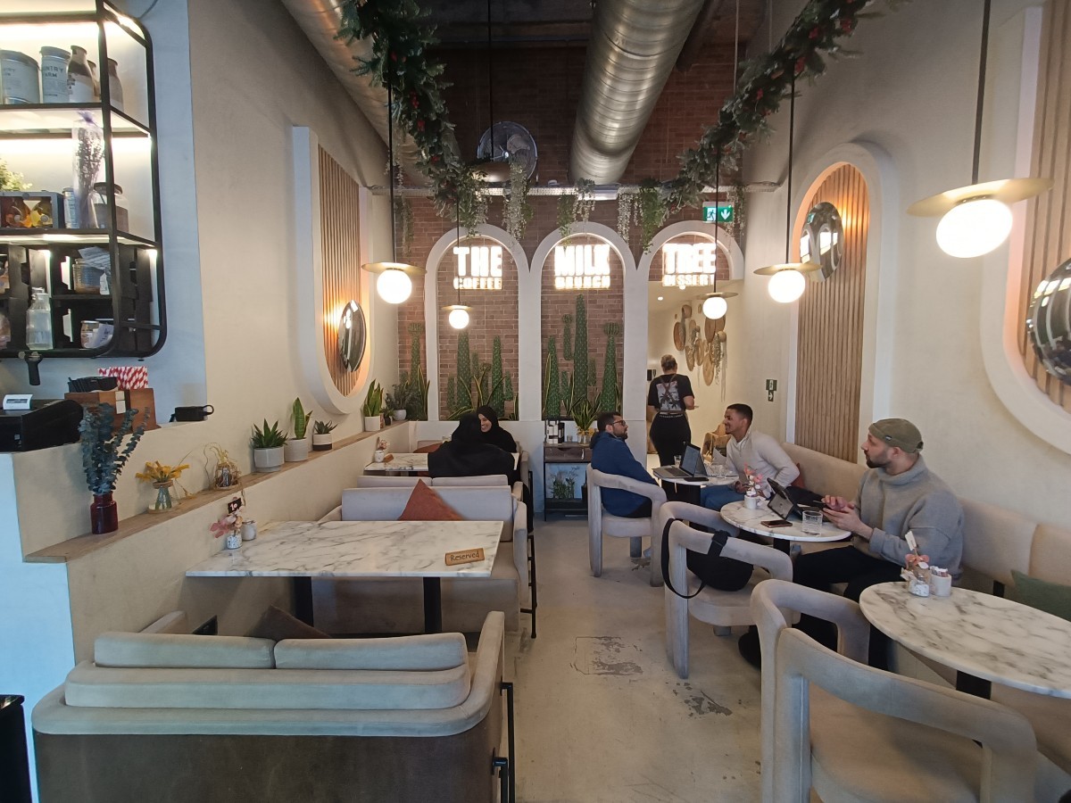 From end of counter, facing straight. Booths along left. Half-booths and chairs along right. Path to bathroom at back right.