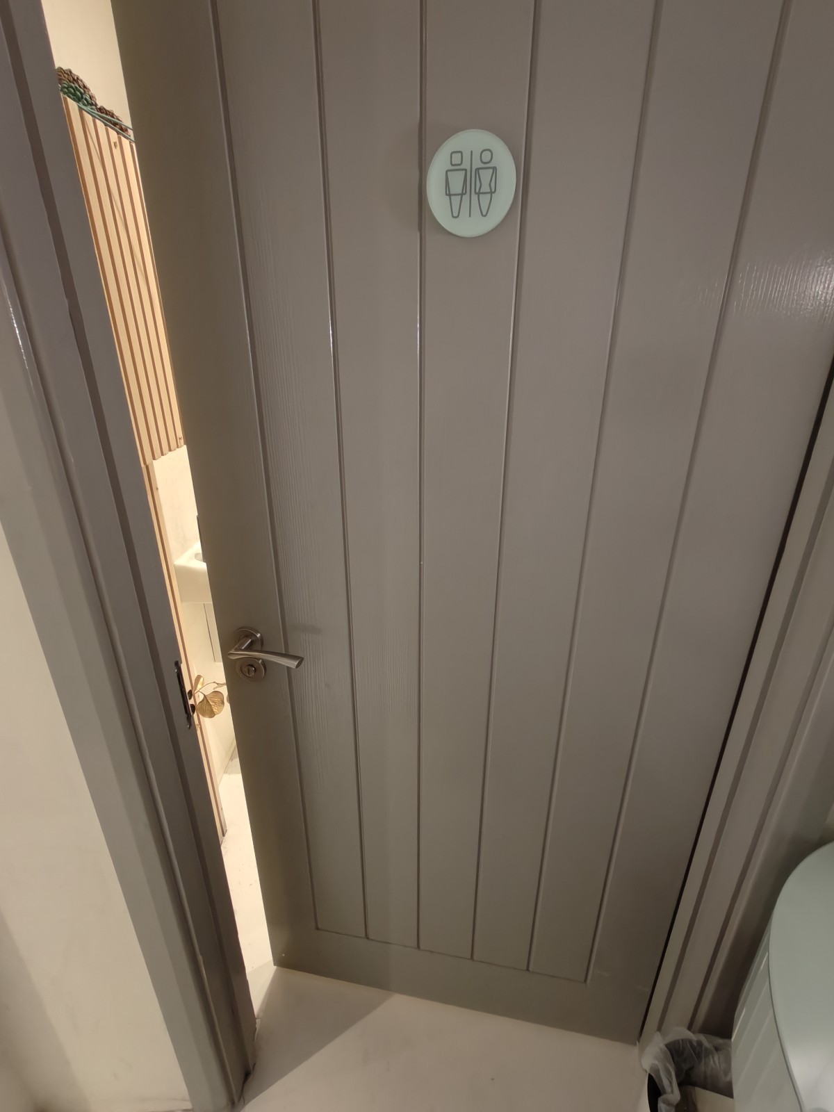 From end of path facing left. Grey toilet door ahead. Push silver handle on left to open.