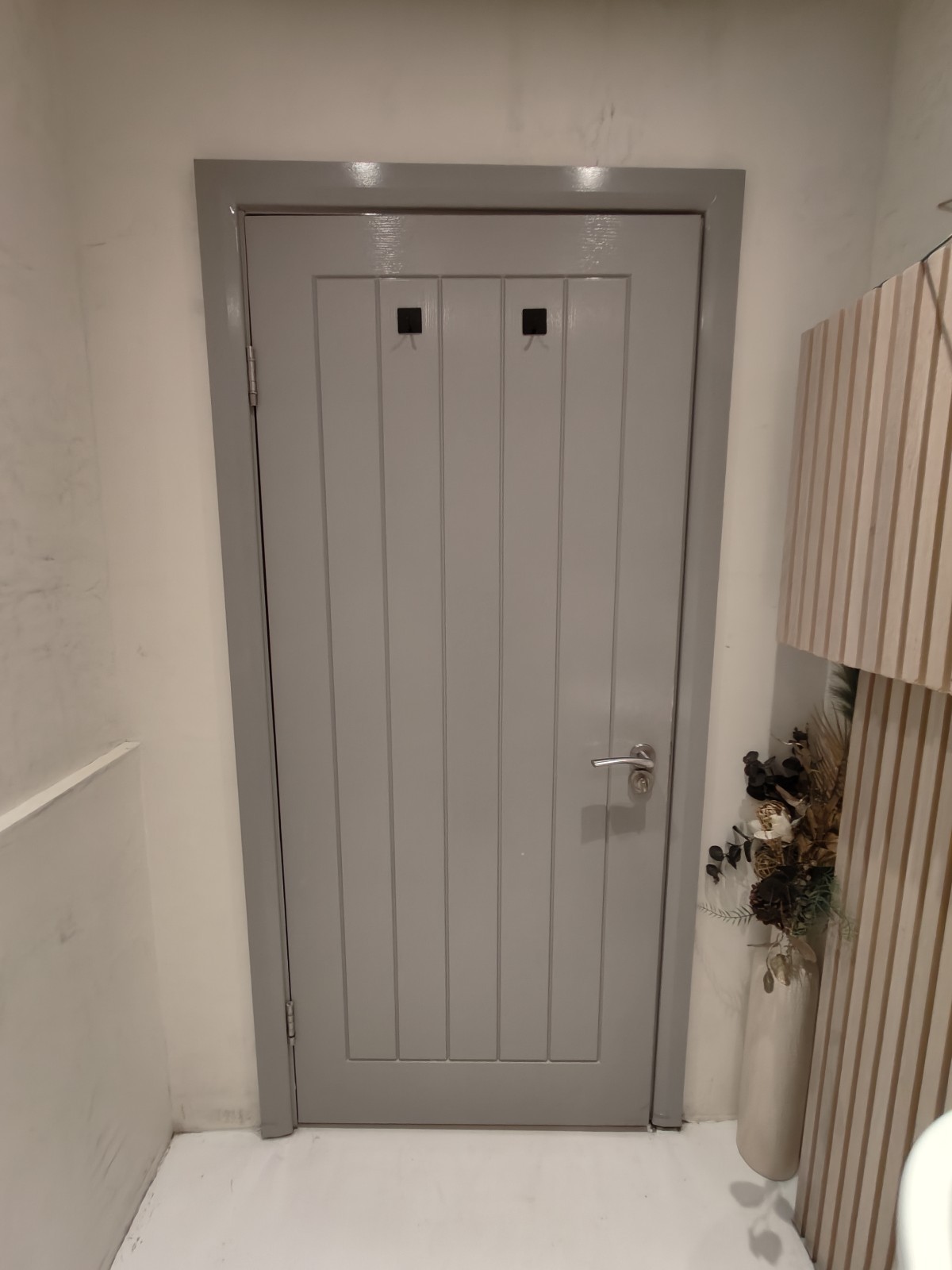 Back of door. High hooks at centre. Pull silver handle on right to open.