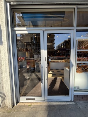 Glass doors with metal frame ahead. Push silver handles in center to open.