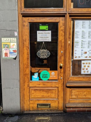 Glass door with wood frame and metal handle. Pull from right to open.