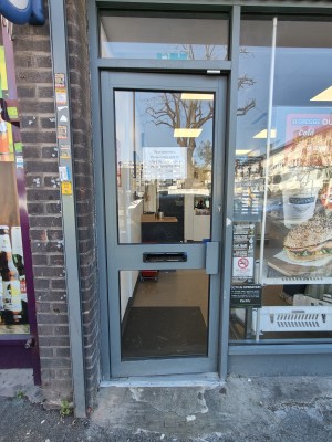 Grey framed glass door. Push grey handle on right to open.