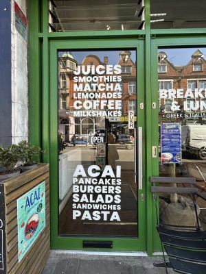 Glass door ahead with white writing and green frame. Push silver handle on right to open.