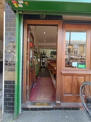 Glass door with brown, wooden frame. Push silver handle on right to open.
