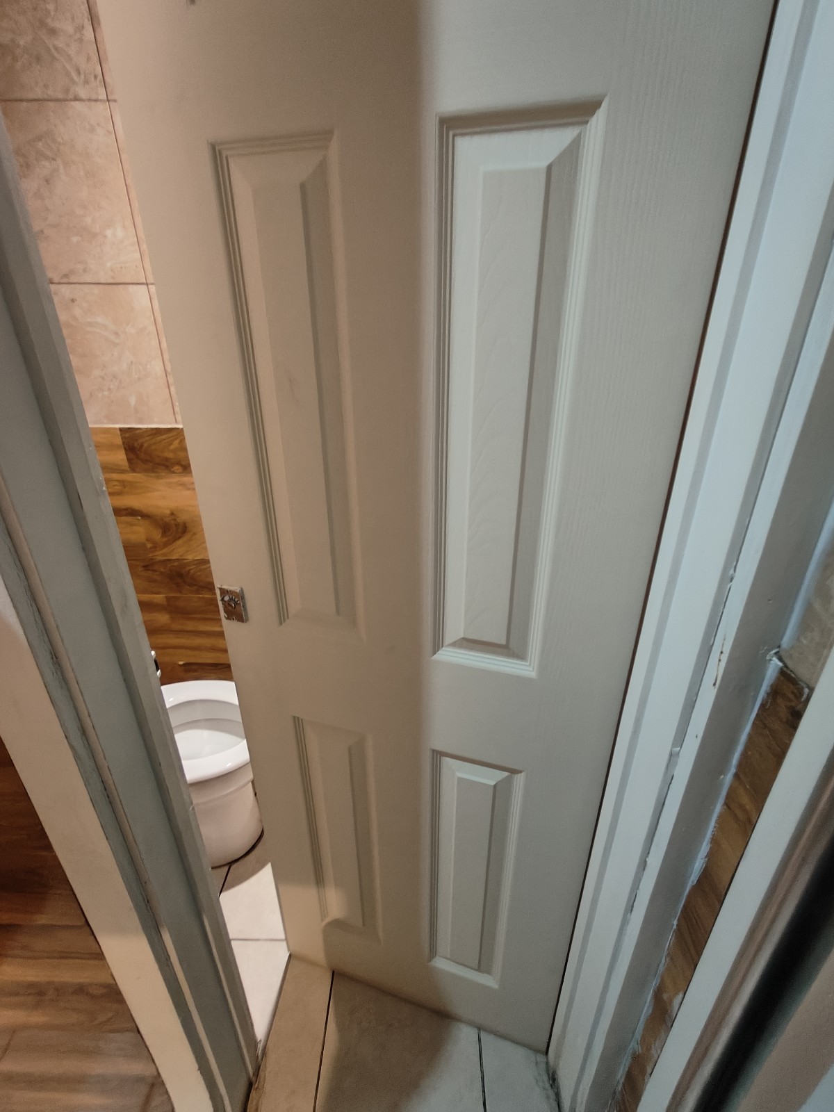 From preceding door facing right. White toilet door ahead. Push from left to open.