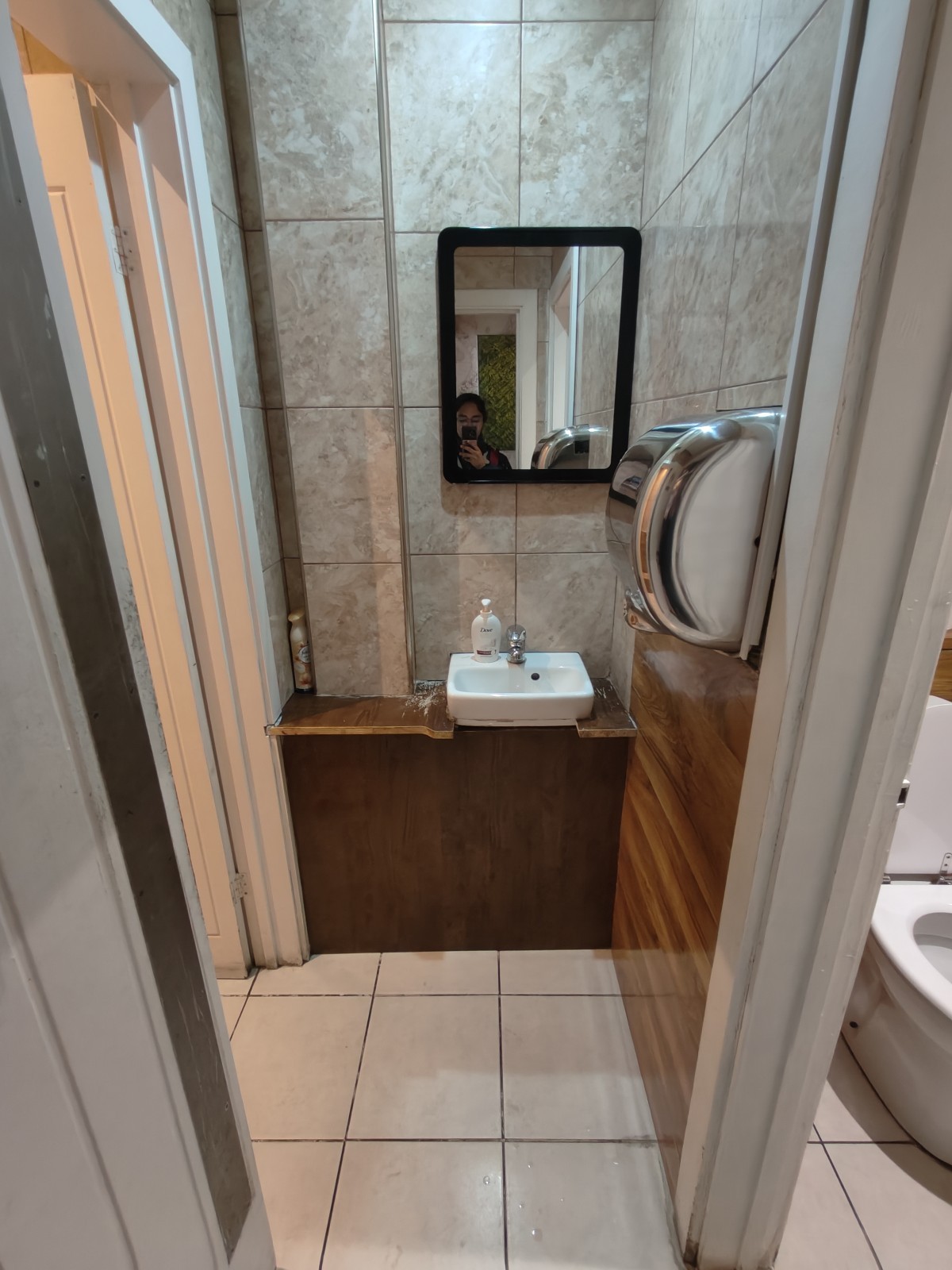 From door facing straight. Cubicle on right. Sink at back. Second cubicle to its left.