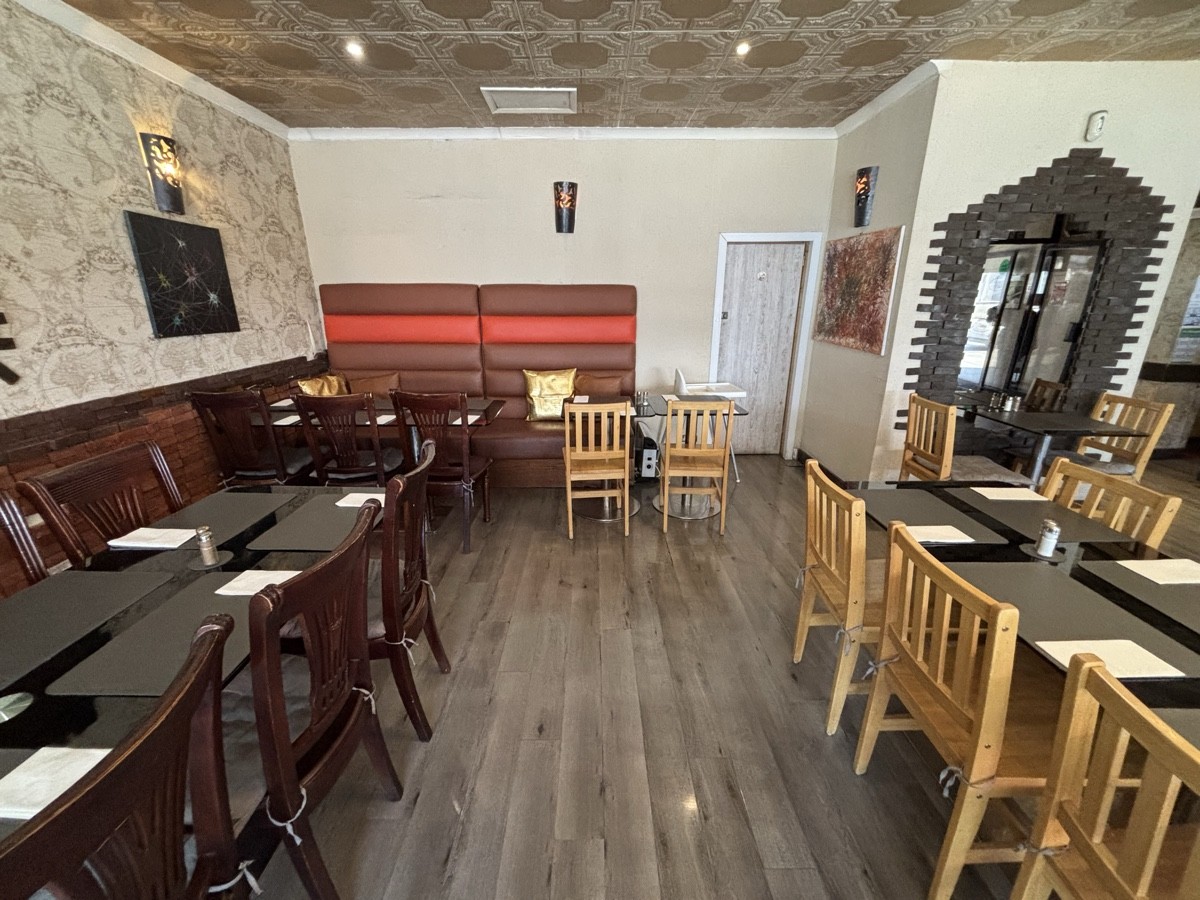 From end of table facing right. Tables and chairs along left and right. Half booth at the back.