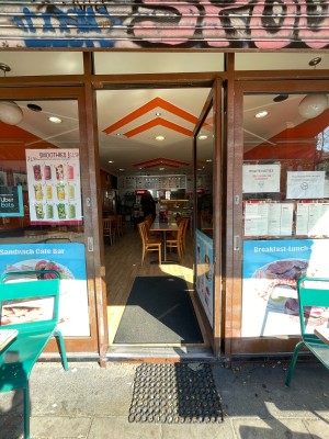 Glass door with brown frame ahead. Push brown metal handle from left to open.