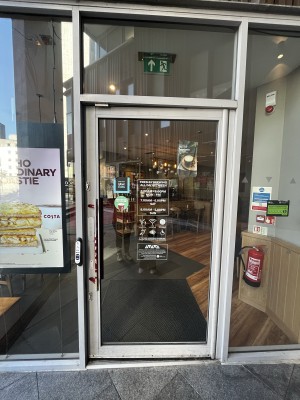 Glass door with metal frame. Push silver handle from left to open. Doorbell to left.