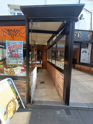 Glass door with black, metal frame. Push from right to open.