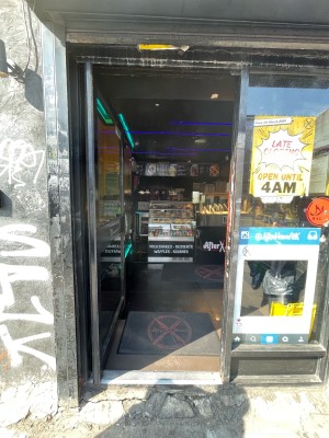 Facing glass door with grey frame. Push on right to open.