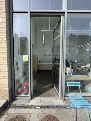 Metal-framed glass door. Push from metal handle on left to open.