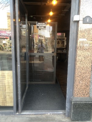 Glass door with black frame. Push handle on right to open.