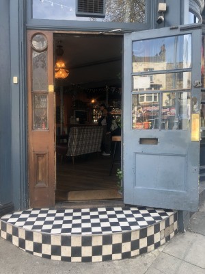 Glass doors with brown frame on left, blue frame on right. Pull handle in centre to open.