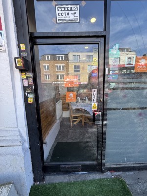 Glass door with black frames. Push from right to open.