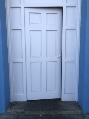 Preceding door ahead. White wooden door, push from right to open.
