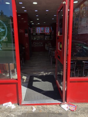 Glass door with red frame. Push handle on left to open.