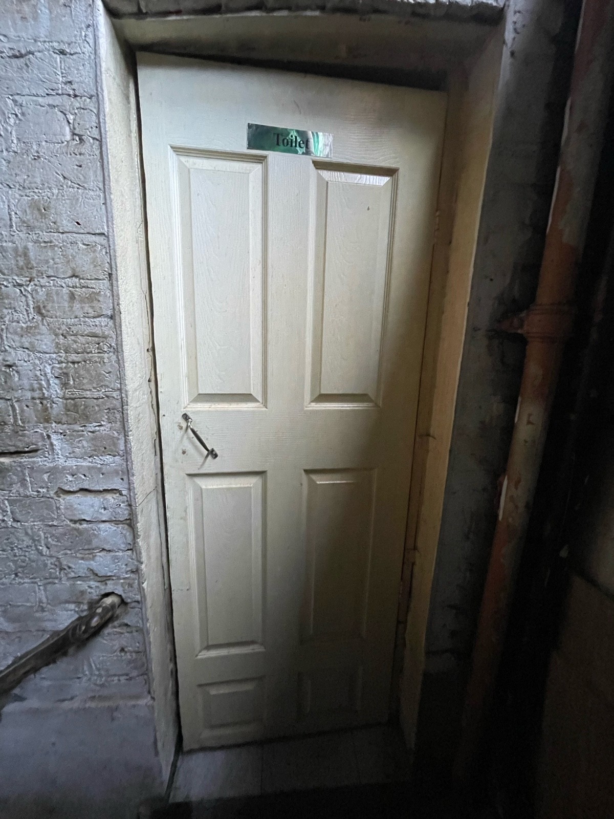 Facing white toilet door. Pull sliver handle on left to open.