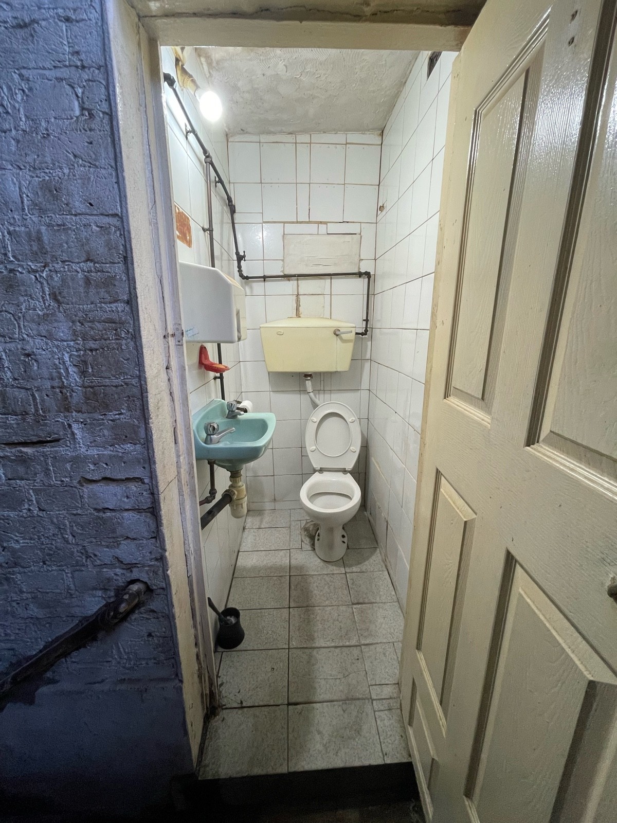 From doorway facing straight. Toilet at back right. Sink at left.