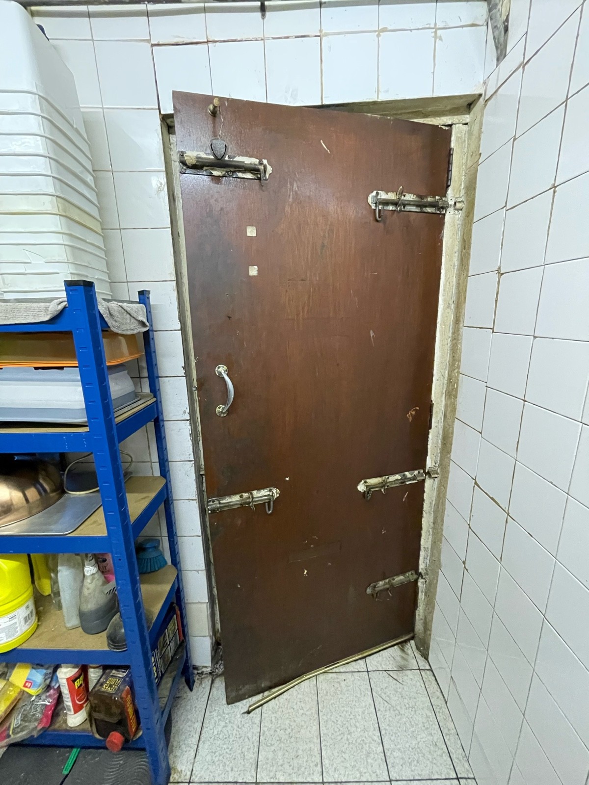 From end of hallway facing right. Preceding wooden door ahead. Pull sliver handle on left.