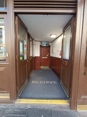 From street, facing venue. Glass doors with brown wooden frames. Push from middle to open.