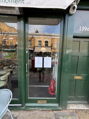 Glass door with green frame ahead. Push via handle on left to open.