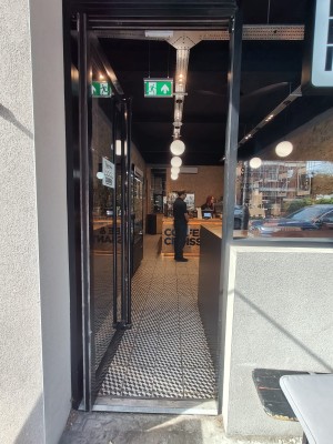 Black framed glass door. Push black handle on right to open.