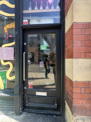 Black framed glass door. Push silver handle on left to open.