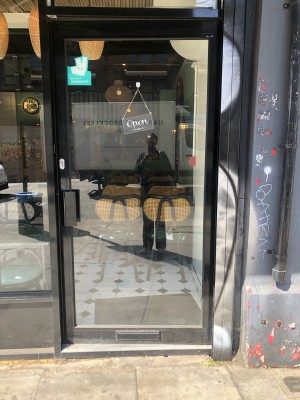 Glass door with black frame. Push handle on left to open.