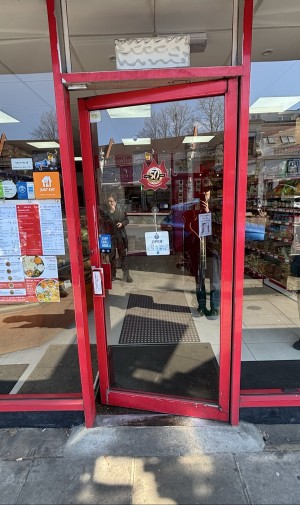 Glass door with red frame. Push door to open via handle on left.