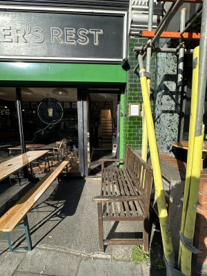 From pavement facing venue. Path ahead obstructed by bench along right. Entrance behind.
