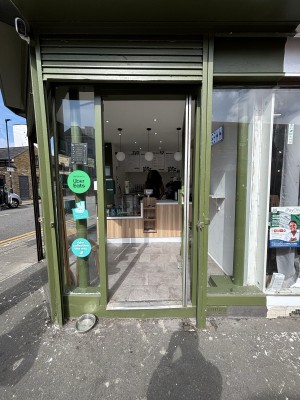 Glass door with green frame ahead. Push door to open via handle on left.