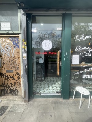 Glass door with green frame ahead. Push wooden handle on right to open.