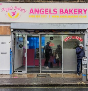 From street facing venue. Grey framed glass doors. Push grey handles in centre to open. Small bump on threshold of doors. Counter straight after door.