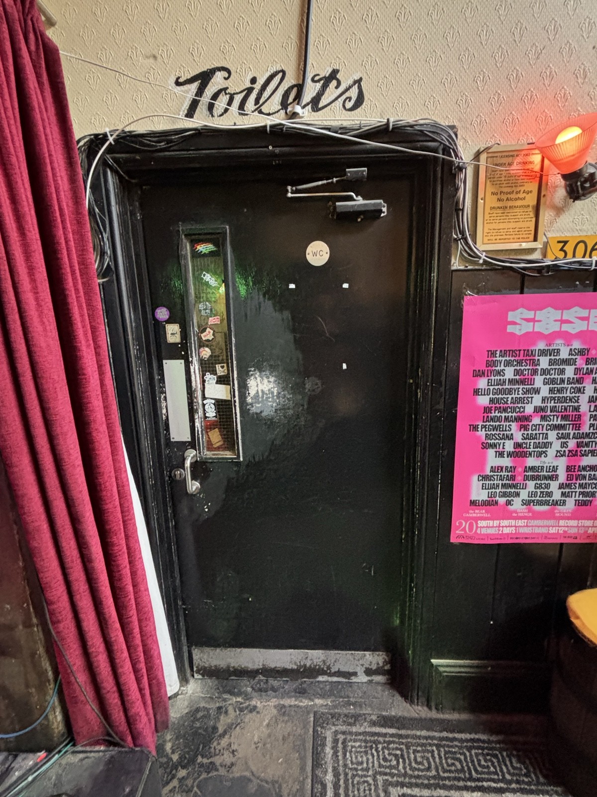 From back of main area facing right. Black door ahead. Push via handle on left to open.