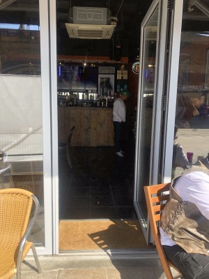 Glass door with white frame. Push handle on left to open.