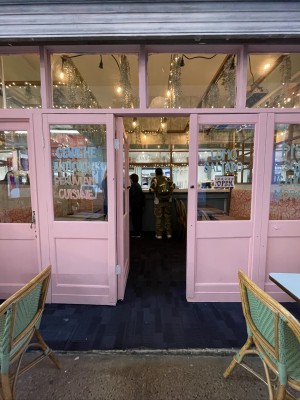 Pink wood-framed glass door. No handle. Push from right to open.