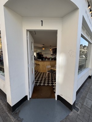 White wooden door. Push from silver handle on right to open.
