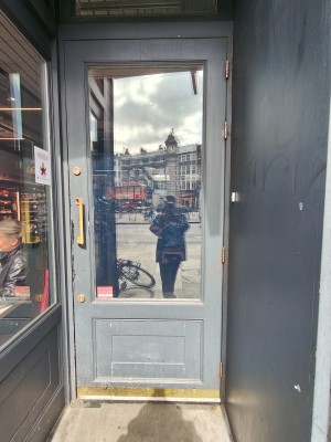 Grey framed glass door. Pull golden handle on left to open. Doorbell on right of door.
