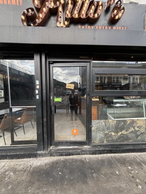 Glass door with black frame ahead. Push via handle on left to open.