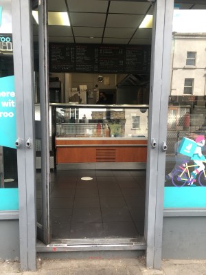Glass door with grey frame. Push handle on right to open.
