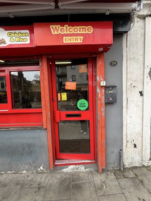 Glass door with red frame. Push via handle on left to open.