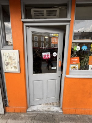 Glass door with grey frames. Push from right to open.