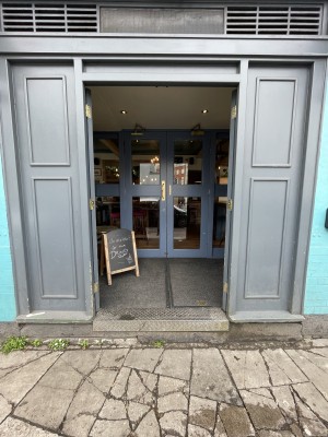 First set of double doors. Blue wooden doors. Push from brass handles at centre to open.