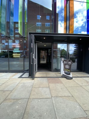 Glass door with black frame ahead. Pull from metal handle on right to open