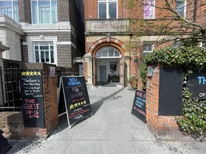 A-frame signs on left and right. Path at centre to first door.