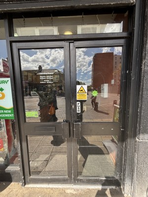 Glass doors with black frames. Push from centre to open.