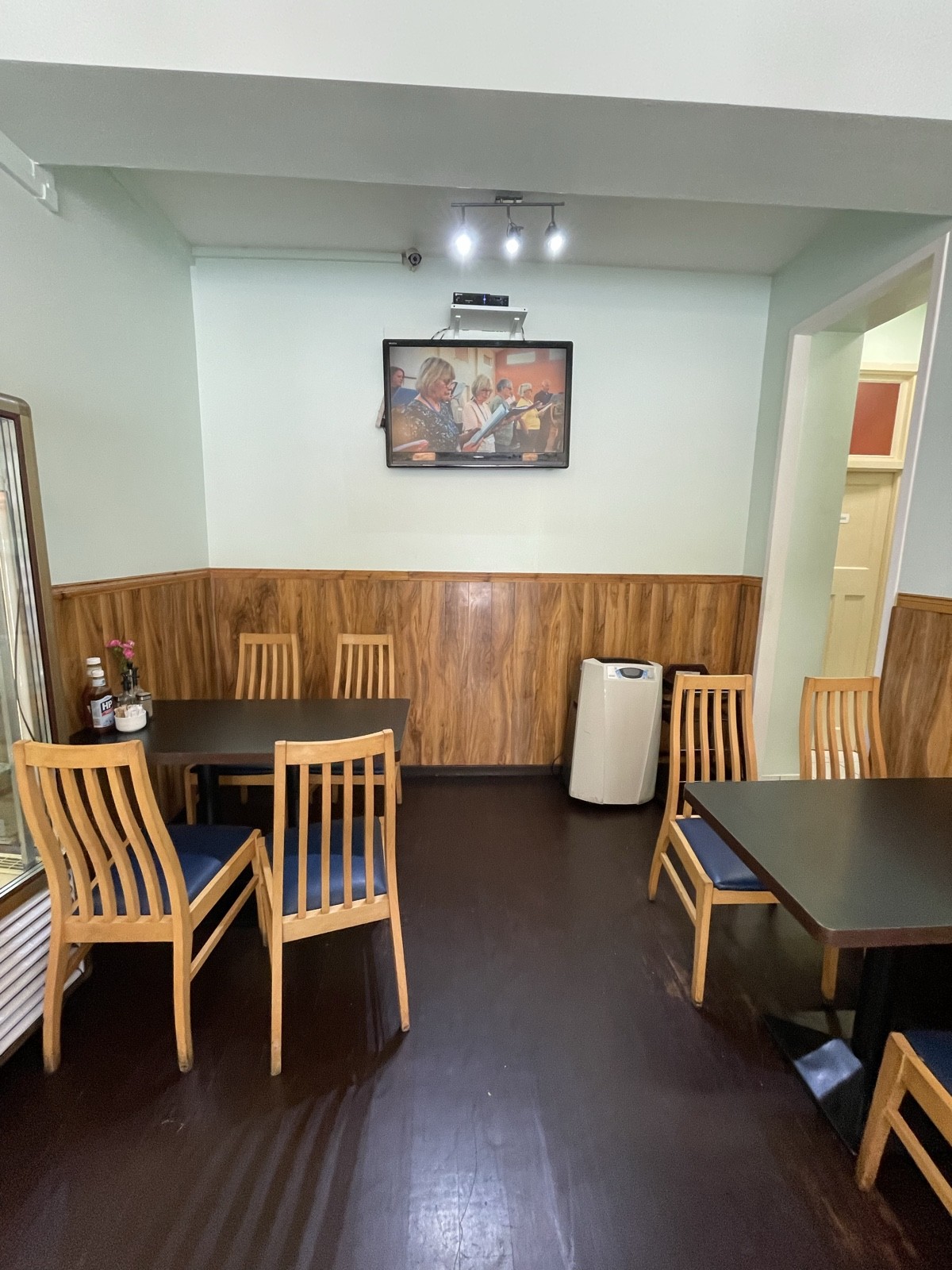 From opening facing left. Tables and chairs on left and right. Bathroom entrance at back right.